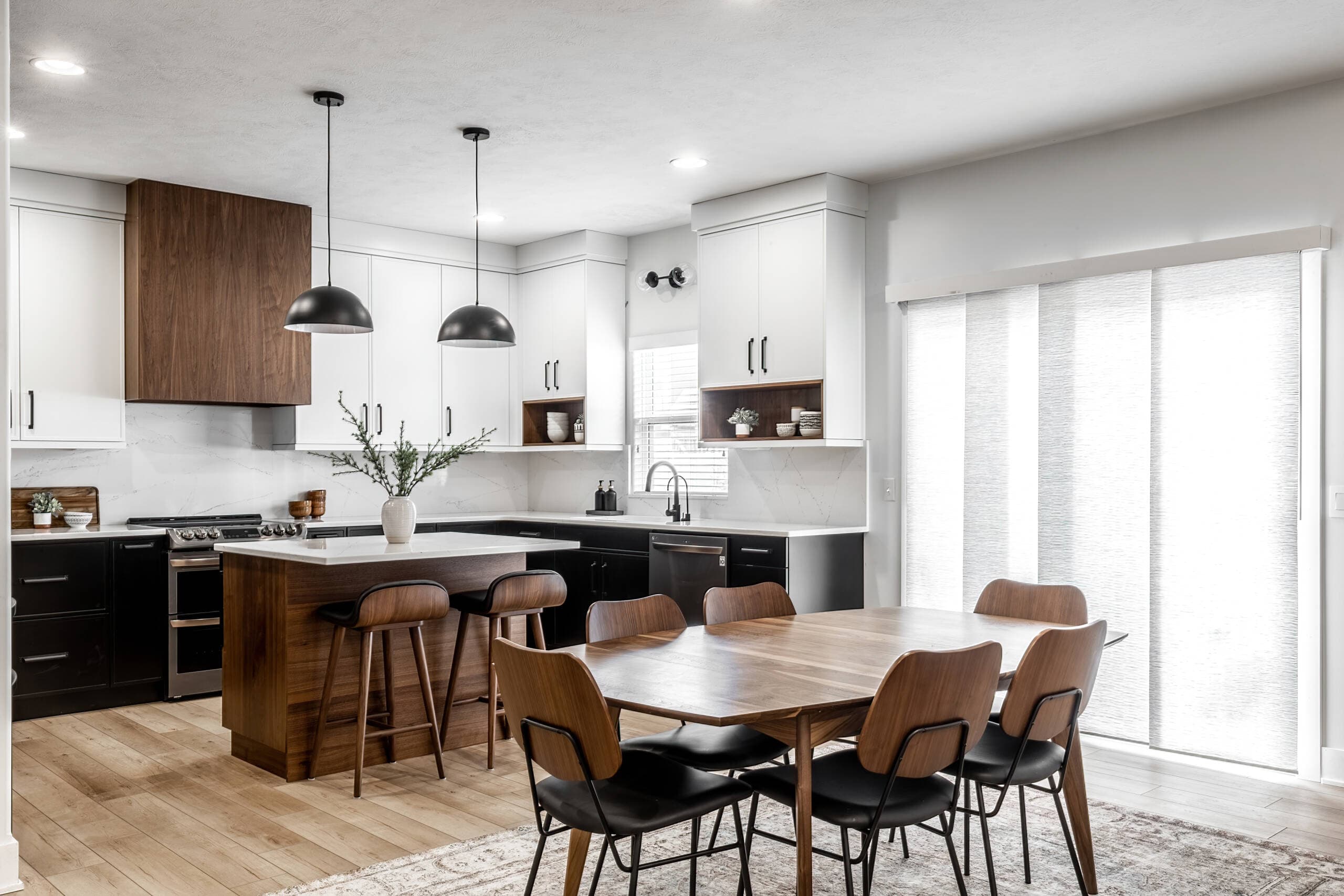 Luxury kitchen remodel in Southlake, TX featuring slim shaker cabinets in black, white, and walnut wood tones with quartz countertops and waterfall island